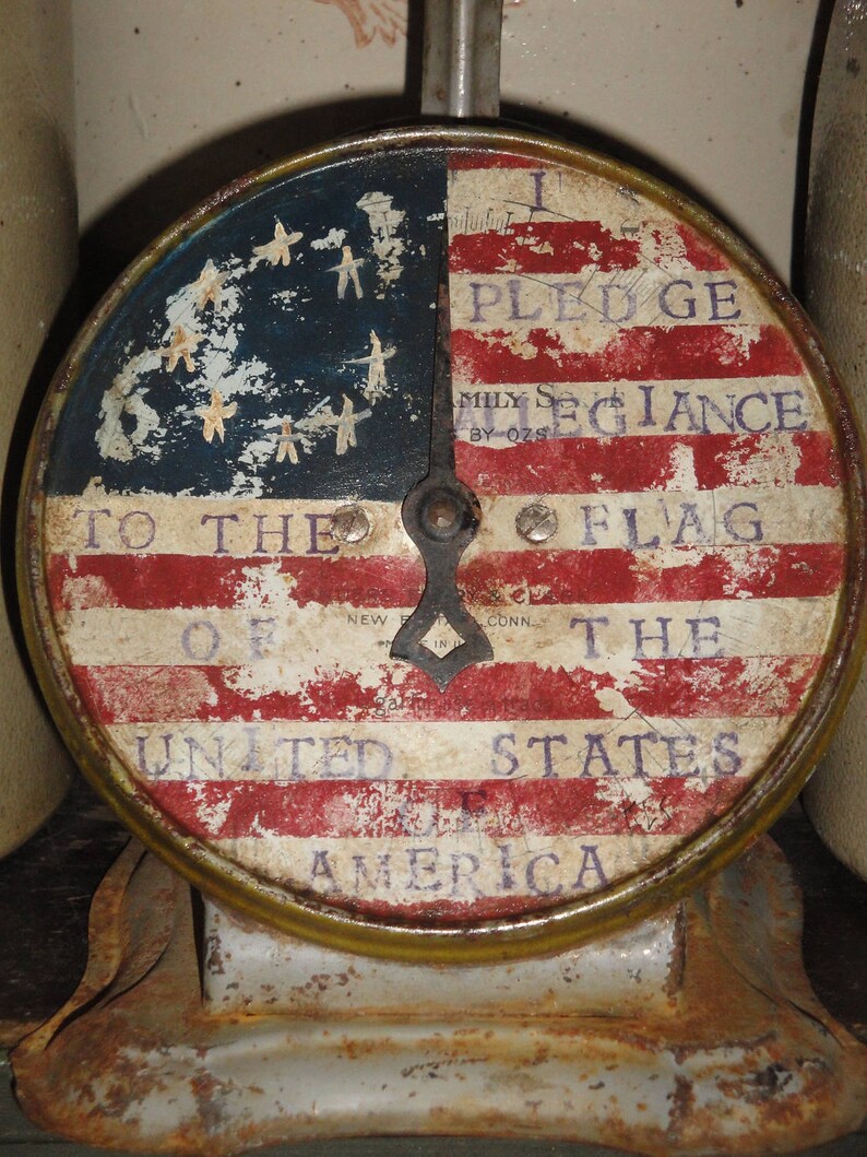 May include: A vintage scale with a red, white, and blue American flag design. The scale reads "I Pledge Allegiance to the Flag of the United States of America".