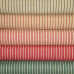 May include: Five rolls of striped fabric in various colors, including red, green, and white. The fabric has a woven texture and a classic, vintage look.