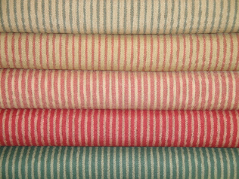 May include: Five rolls of striped fabric in various colors, including red, green, and white. The fabric has a woven texture and a classic, vintage look.