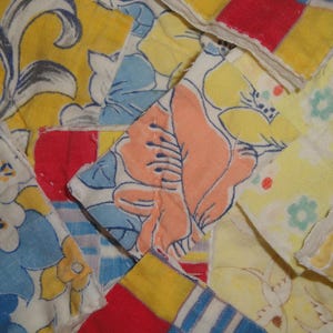 May include: A collection of fabric scraps in various colors and patterns, including yellow, blue, red, and white. The fabrics are arranged in a random pattern, creating a patchwork effect.