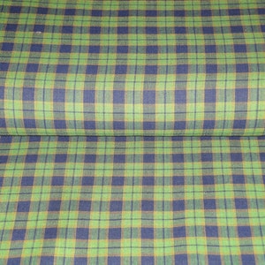 May include: Green, blue, and brown plaid fabric. The fabric has a woven texture.