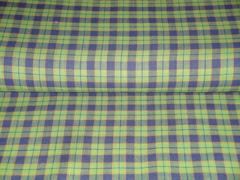 May include: Green, blue, and brown plaid fabric. The fabric has a woven texture.