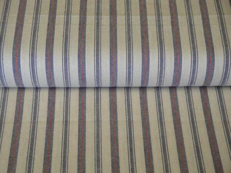 May include: A roll of cream-coloured fabric featuring vertical stripes in navy blue and red. The stripes are evenly spaced, creating a classic, textured appearance. This textile is suitable for various home decor projects. The fabric is rolled, showing the pattern.
