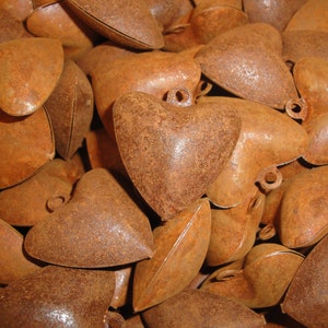 May include: A pile of rustic, heart-shaped metal ornaments in shades of brown and orange. The hearts are slightly uneven and have a distressed, aged look.
