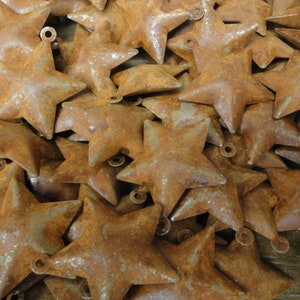 May include: A pile of rustic, rusty metal star ornaments. The stars are all the same size and shape, and they have a distressed, aged look.