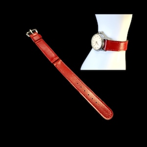 May include: A wristwatch featuring a round silver-tone case with a white dial and a textured red leather strap. The watch is shown both detached and fastened, highlighting the vibrant red band with a silver-tone buckle and matching hardware.