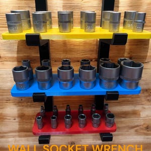 May include: A wall-mounted socket wrench holder with three shelves. The top shelf is yellow, the middle shelf is blue, and the bottom shelf is red. The shelves are filled with various sizes of socket wrenches.