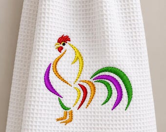 May include: A white waffle-weave kitchen towel featuring an embroidered rooster design. The rooster is composed of stylized, curved lines in vibrant colors including red, yellow, purple, and green, creating a colorful graphic on the fabric.