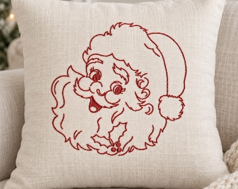 May include: A square throw pillow made of light beige, textured fabric featuring a red embroidered line art illustration of a smiling Santa Claus face wearing a hat, with a holly sprig accent at the bottom of the beard and mustache.
