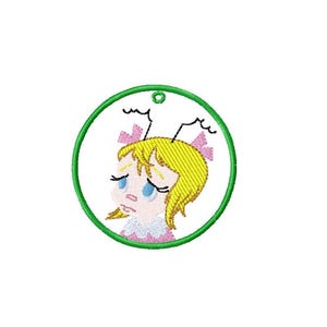 May include: Embroidered patch featuring a cartoon girl with blonde hair, blue eyes, and a sad expression. She wears a pink dress and has pink bows in her hair. The design is enclosed in a green circle.