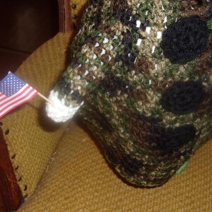 Puede incluir: Una peque&ntilde;a bandera estadounidense est&aacute; unida a un palo de madera y colocada en una silla de tela marr&oacute;n y beige. La bandera es roja, blanca y azul. La silla est&aacute; cubierta de una tela marr&oacute;n y beige con un patr&oacute;n tejido.