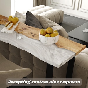 May include: A custom-made sofa table with a white marble top and a natural wood edge. The table has black metal legs and is decorated with pears in a marble bowl and on a white cutting board. The text "Accepting custom size requests" is visible.