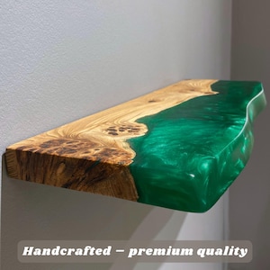 May include: A rectangular wall shelf featuring a natural live-edge wood slab with prominent grain and knots, seamlessly joined to a translucent, vibrant emerald green resin section. The text "Handcrafted – premium quality" is visible.
