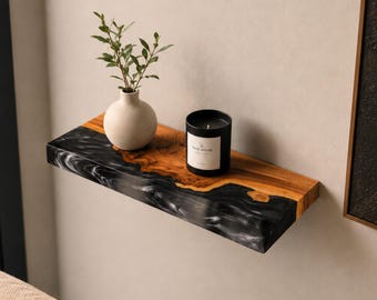 May include: A rectangular floating shelf made of natural wood and black resin with white marble-like swirls. A small white vase with green leaves and a black candle with a white label sit on the shelf. The text "Accepting custom size requests" is visible.
