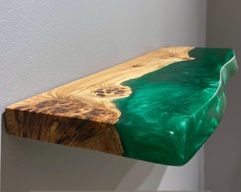 May include: A rectangular wall shelf featuring a natural live edge wood slab with prominent grain patterns and knots, seamlessly joined to a translucent, vibrant emerald green resin section that mimics a flowing river edge.