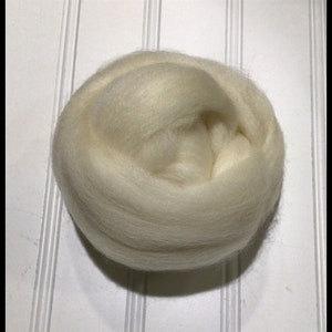 May include: A ball of cream-colored wool roving, tightly wound and ready for fiber art projects. The text "Chestnut Junction" is displayed in a black, stylized font at the bottom of the image.