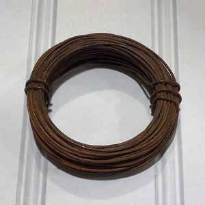 May include: A coil of brown wire, likely used for crafts or jewelry making.