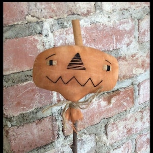 May include: An orange pumpkin decoration with a stitched face and a twig stem. The pumpkin features a zig-zag mouth, triangle nose, and rectangular eyes. The text "Chestnut Junction" is at the bottom of the image. Ideal for autumn decorations.