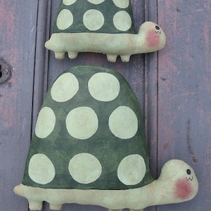 May include: Two green and white polka dot turtle figurines. The turtles are made of fabric and have a whimsical, handmade look.