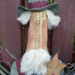 May include: A handmade rag doll with a blue and white hat, a white beard, and a red, white, and blue patterned shirt. The doll is holding a brown star.