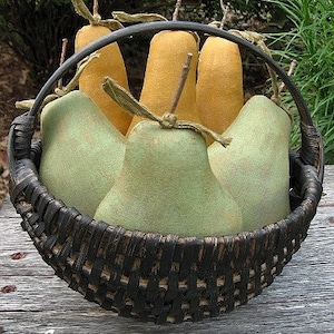 Op de afbeelding: Een zwarte rieten mand gevuld met groene en gele peren. De mand heeft een zwarte handgreep en staat op een houten oppervlak. De tekst "Chestnut Junction" is zichtbaar onderaan de afbeelding.