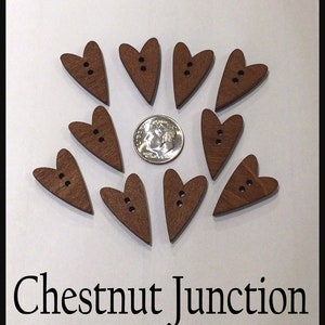 May include: Ten wooden heart-shaped buttons with two holes each. The buttons are a dark brown color and are arranged in a circle around a US dime.