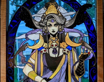Puede incluir: Un panel de vidriera en un marco de madera que representa una figura de pelo largo, con túnicas doradas y moradas, adornada con lunas crecientes, detalles de calaveras y una gema morada central sobre un fondo azul oscuro arqueado.
