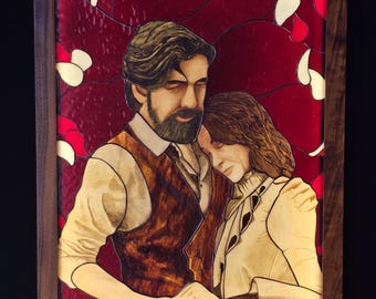 Puede incluir: Un panel rectangular de vidriera en un marco de madera oscura que representa a un hombre con barba y una mujer apoyada en su hombro. Se toman de la mano sobre un fondo rojo intenso lleno de formas de pétalos blancos y rojos dispersos.