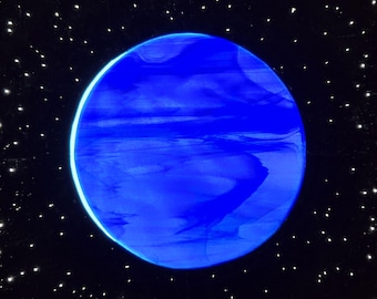 Puede incluir: Una pieza de arte mural circular que representa un planeta azul vibrante con texturas marmoladas en espiral. El planeta se sitúa sobre un fondo negro profundo lleno de numerosos puntos blancos dispersos que parecen estrellas lejanas.