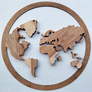 May include: A wooden world map, cut from light-colored wood, is set within a brown circular frame. The continents are individually cut and arranged to form the world map. The background is white.