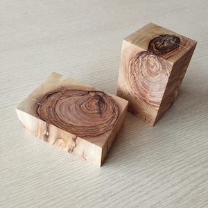 Peut inclure: Deux morceaux de bois avec une finition en bois naturel. Le bois présente un motif de grain unique avec des anneaux brun foncé. Les pièces sont de forme rectangulaire et de tailles différentes.