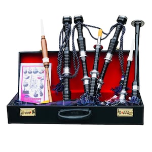 Puede incluir: Un juego de gaita en un estuche negro con interior rojo. Las gaitas son negras con detalles plateados y cordones azules. También se ven un puntero de madera y una tabla de digitación. El estuche tiene un asa y una cerradura de combinación.