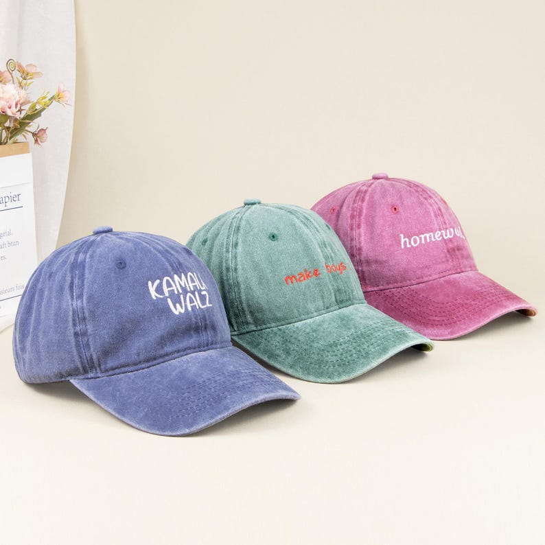 May include: Three baseball caps in blue, green, and pink with a distressed, washed-out finish. The blue cap features the white text KAMALA WALZ, the green cap has red text reading make boys, and the pink cap displays white text reading homew.