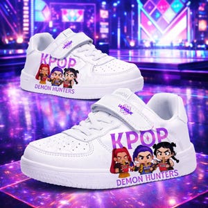 May include: White trainers with hook-and-loop straps. The shoes display the word "KPOP" in purple, alongside cartoon illustrations of three characters and the text "DEMON HUNTERS". A purple logo is on the strap.