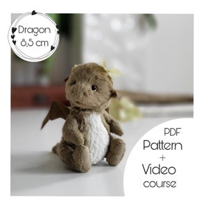 Könnte beinhalten: Ein braunes Plüschdrachenspielzeug mit weißem Bauch, das auf einer weißen Oberfläche sitzt. Der Drache ist 8,5 cm groß. Das Bild enthält den Text "Dragon 8,5 cm" und "PDF-Muster + Videokurs".
