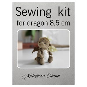 Puede incluir: Un kit de costura para un dragón de 8,5 cm de altura. La imagen presenta un juguete de dragón de peluche con pelaje marrón, vientre blanco y pequeñas alas marrones. El texto "Sewing kit for dragon 8,5 cm" se muestra en la parte superior.
