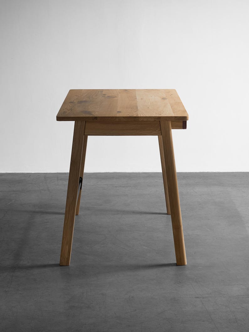 May include: A light brown wooden table with a rectangular top and four tapered legs. The table features a natural wood grain pattern throughout the surface and structure, showcasing a simple, functional design with clean lines and a smooth finish.