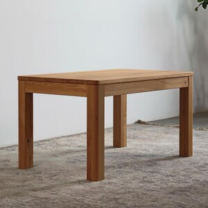 May include: A rectangular dining table crafted from light brown wood with a visible grain pattern. The table features four sturdy, straight legs and a smooth, flat top surface. The construction shows clean lines and a natural wood finish throughout.