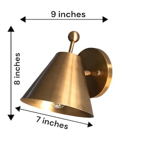 A Traditional Brass Wall Sconce Pair Is Pictured at An Angle, with Both Handcrafted Fixtures Displaying Decorative Finial Accents and Round Wall Canopies. the Matching Solid Brass Forms Create Coordinated Lighting with A Classic Appearance Suited to Vintage and Transitional Interiors, Frost Lights.