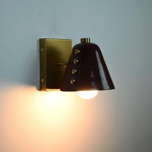 Close View of A Handmade Wine Shade Wall Lamp with A Cone Profile and Brass Detailing, Emphasizing the Deep Shade Color, Clean Silhouette, and Decorative Rivet Accents of This Distinctive Wall Fixture, Frost Lights.