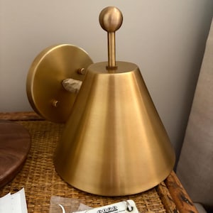 Close Angled Perspective of A Brass Wall Sconce Pair Highlighting the Decorative Finial, Solid Brass Construction, and Traditional Silhouette. the Matching Fixtures Are Designed as A Coordinated Set, Offering a Classic Visual Detail for Bedrooms, Hallways, Entryways, and Living Areas, Frost Lights.