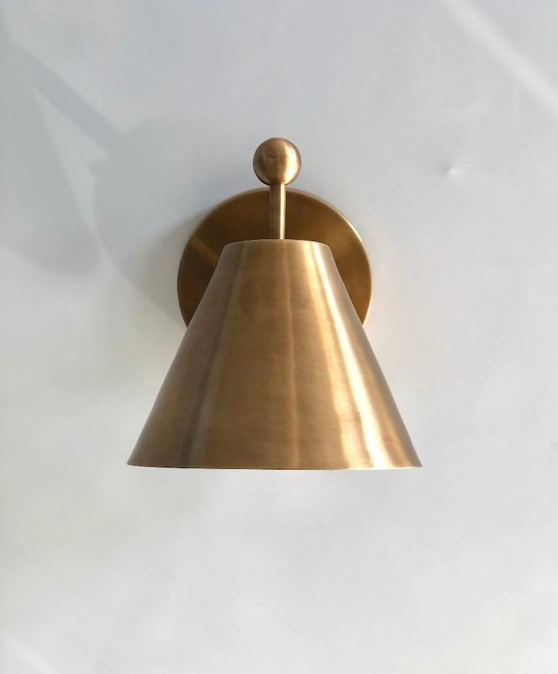 This Handcrafted Pair of Brass Wall Sconces Is Shown from The Front, Emphasizing the Symmetrical Appearance of Two Matching Fixtures with Finial Accents. Their Classic Proportions and Warm Brass Surfaces Create a Traditional Decorative Lighting Arrangement for Indoor Spaces, Frost Lights.