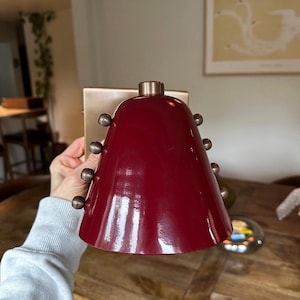 This Handmade Wall Sconce Features a Tapered Wine Shade Mounted to A Brass Structure, Photographed to Show Its Compact Size, Warm Material Contrast, and Understated Decorative Rivet Detailing, Frost Lights.