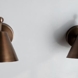 A Coordinated Pair of Handcrafted Brass Wall Lamps Is Shown from A Three Quarter Angle, Revealing the Finial Details, Round Canopies, and Classic Proportions. Each Fixture Measures 8 Inches High and 7 Inches Wide, Creating an Elegant Traditional Wall Lighting Arrangement, Frost Lights.