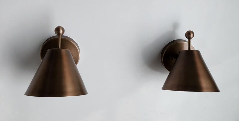 A Coordinated Pair of Handcrafted Brass Wall Lamps Is Shown from A Three Quarter Angle, Revealing the Finial Details, Round Canopies, and Classic Proportions. Each Fixture Measures 8 Inches High and 7 Inches Wide, Creating an Elegant Traditional Wall Lighting Arrangement, Frost Lights.