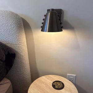 Product Detail of A Wine Shade Brass Wall Sconce Showing the Cone-Shaped Shade, Metal Framework, and Decorative Rivets, with The Contrasting Materials Creating a Warm and Sophisticated Visual Effect, Frost Lights.