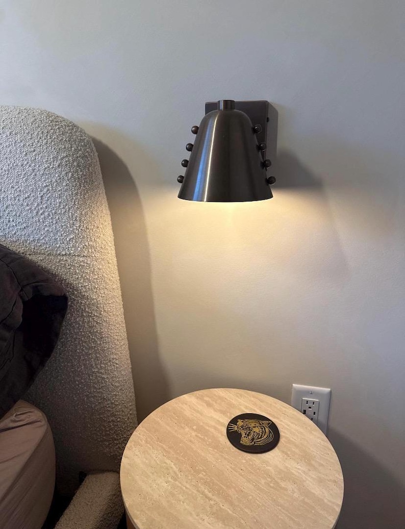 Product Detail of A Wine Shade Brass Wall Sconce Showing the Cone-Shaped Shade, Metal Framework, and Decorative Rivets, with The Contrasting Materials Creating a Warm and Sophisticated Visual Effect, Frost Lights.