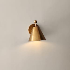 Two Matching Solid Brass Wall Sconces Are Pictured Together, Each Featuring a Decorative Finial Accent and Classic Silhouette. the Handcrafted Fixtures Have a Warm Metallic Character and Traditional Styling Suited to Bedrooms, Entryways, Stairways, Hallways, and Living Rooms, Frost Lights.