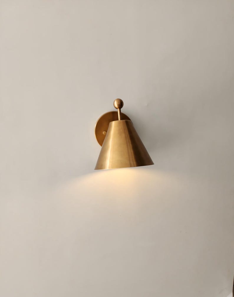 Two Matching Solid Brass Wall Sconces Are Pictured Together, Each Featuring a Decorative Finial Accent and Classic Silhouette. the Handcrafted Fixtures Have a Warm Metallic Character and Traditional Styling Suited to Bedrooms, Entryways, Stairways, Hallways, and Living Rooms, Frost Lights.