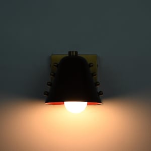 This Compact Cone Wall Sconce Combines a Wine Colored Shade with Handcrafted Brass Components, Creating a Bold Contrast Between the Rich Shade and Warm Metal While Maintaining a Simple Architectural Form, Frost Lights.